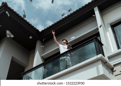 Rich Dude Throwing Money Up In The Sky At House Balcony.