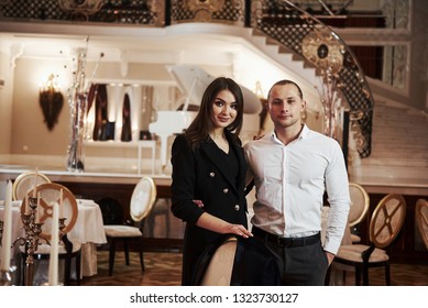 Rich Family Members. Stands Against Stage With Piano. Beautiful Couple Have Romantic Dinner In Luxury Restaurant At Evening Time.