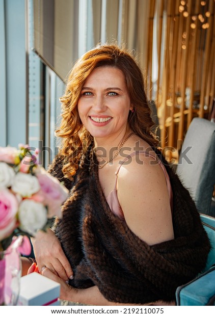 Rich happy bride.\
Woman  in a mink fur cape. Fur cape elegantly opens the shoulder. A\
woman celebrates her wedding day in a restaurant. Natural beautiful\
smile in adulthood.