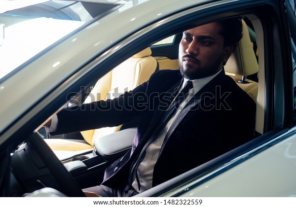 Rich indian\
businessman in formal wear drive car\
.