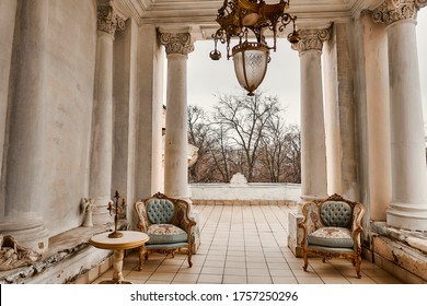 Rich interior of studio with gold decorations on the walls. Large white columns. Balcony or loggia, interior in the style of Borocco.