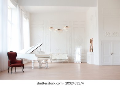 Rich luxury interior of a classic style room with vintage furniture, big windows, mirror, chandeliers and grand piano.