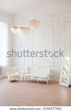 Rich luxury interior of a classic style room with vintage furniture, big windows, mirror, chandeliers and elegant sofa.