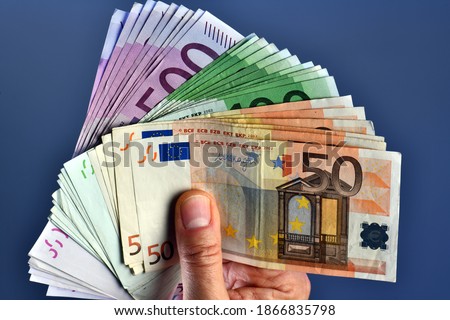 A rich man hand shows thousands of Euros in 50 euro 100 euro and 500 euro banknotes on a blue background. wealth concept, concept of wealth