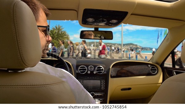 Rich man in sunglasses waiting for green\
light while sitting in expensive\
car