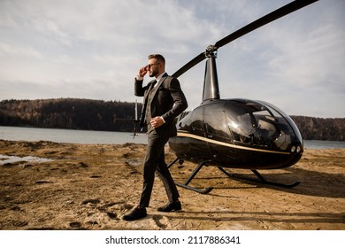 Rich man talking on the phone with business partners. Helicopter stands on the beach - Shutterstock ID 2117886341