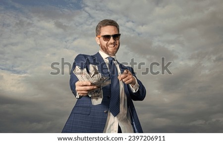 rich millionaire man with money pointing finger on sky background. rich millionaire man