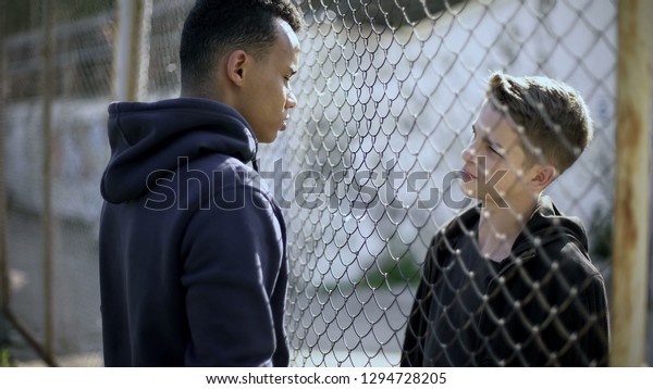 Rich and poor separated by fence, two boys of\
different nationalities\
talking