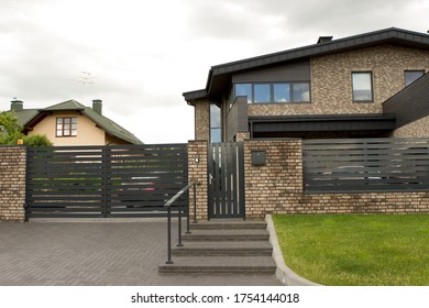 A rich private well-kept house with a classic, elegant, simple design. Black roof and fence, brick facade, in the courtyard of the car. A suburb of a big city. - Shutterstock ID 1754144018