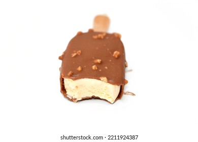 Rich vanilla flavored ice cream in cracking brown milk chocolate and roasted almond isolated, Vanilla ice cream stick coated and covered with a layer of dark chocolate with nuts, selective focus
