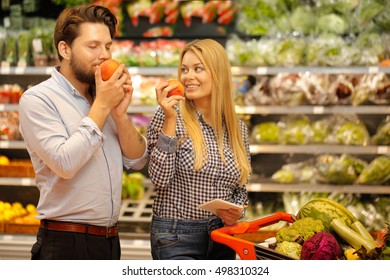 Rich in vitamins. Beautiful young couple inspecting fruits at the supermarket smelling peaches enjoying the fresh aroma of the fruits copyspace - Powered by Shutterstock