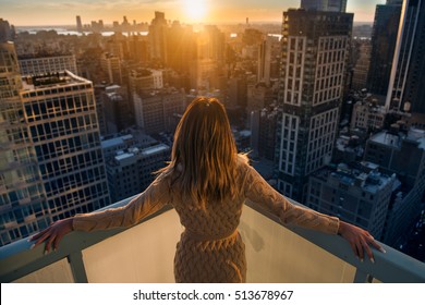 Rich woman enjoying the sunset standing on the balcony at luxury apartments in New York City. Luxury life concept. Successful businesswoman relaxing. - Powered by Shutterstock
