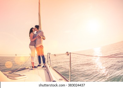 Rich Young Couple In Love On Sailboat Cheering At Sunset - Happy Wander Lifestyle Concept Sailing Around World - Soft Focus On Rose Quartz Filter - Lens Flare And Tilted Horizon As Part Of Composition