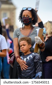 Richmond, North Yorkshire, UK - June 14, 2020: A strong female leader wears a Black Lives Matter PPE face mask and hugs her Superhero son at a BLM protest in Richmond, North Yorkshire