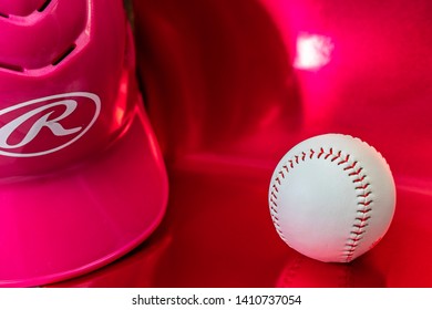 Richmond, Texas, USA - May 29, 2019 - A White Baseball  And Pink Batting Helmet On A Red Background