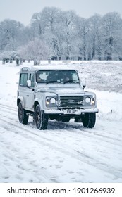 Richmond Upon Thames, London | UK -  2021.01.24: Classic Land Rover Defender On The Snowy Road Of Richmond Park