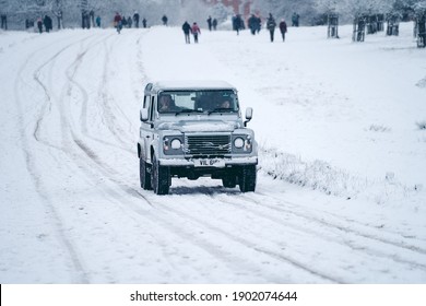 Richmond Upon Thames, London | UK -  2021.01.24: Classic Land Rover Defender On The Snowy Road Of Richmond Park