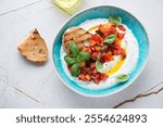 Ricotta dipping sauce with chopped tomatoes in a turquoise bowl, horizontal shot on a white granite background, elevated view