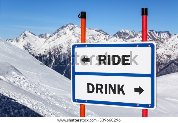 Ride or drink dilemma ski sign with arrows\
showing opposite directions against snowy mountain peak and blue\
sky winter background