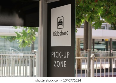 Ride Share Sign With A Picture Of A Car In A Box. Black And White Sign. Green Leaves On A Tree Widows And A Metal Fence In The Background . Also Has Pick-up Zone On The Bottom