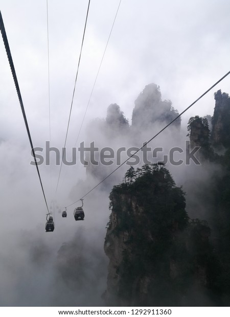 Ride to the top of sandstone pillars, cloud, Pine\
trees (Pinus tabuliformis) and the cable cars by cable car. At\
Zhangjiajie National Forest Park (The Avatar Mountains), Hunan,\
China.