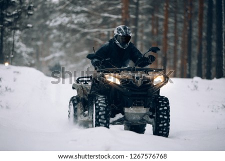 Rider driving in the quadbike in winter in the forest 