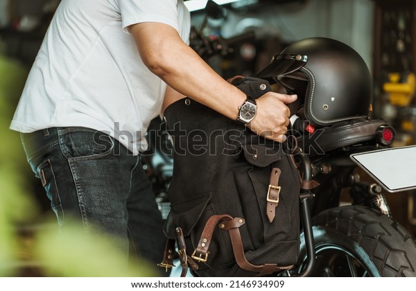rider install a motorcycle saddlebag or side bag\
on luggage bracket  vintage motorbike. motorcycle travel concept.\
selective focus\
