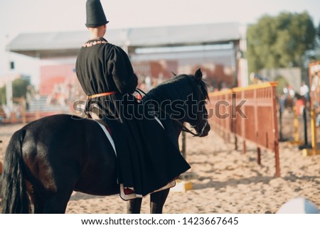 Rider man in medieval clothes on a black horse