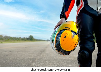 rider motorbike holding his motorcycle helmet walking in the road riding with soft-focus and over light in the background