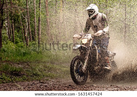 rider on enduro motorcycle riding splash on water and mud