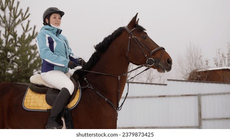 Rider on horse walking in winter. Horse riding in snowy winter. A young female equestrian rides a white horse on a cloudy winter day. - Powered by Shutterstock