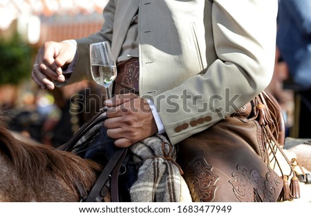 Rider on horseback dressed in traditional costume and holding glass of dry white wine called 