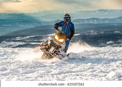Гонщик на снегоходе в горах горнолыжного курорта в Амуте Россия.