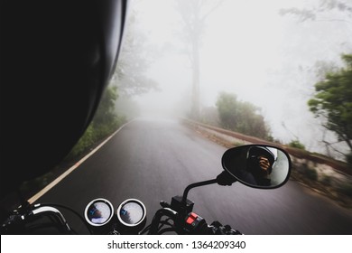 A Rider And A Pillion Ride Up A Cloud Covered Road  