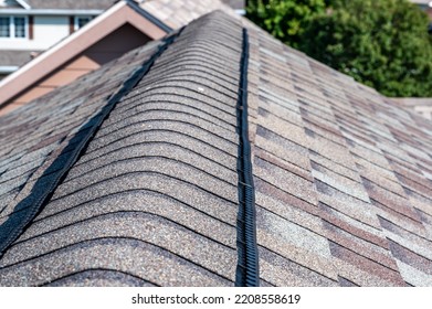 Ridge cap vent installed on a shingle roof for passive attic ventilation on a residential house.  - Shutterstock ID 2208558619