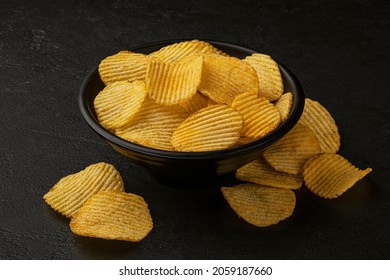Ridged potato chips on black background 