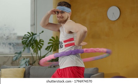 Ridiculous Caucasian Guy In Retro Sportswear Spinning A Hola Hoop Exercise Having Fun Grimacing Playing Comical During Fitness Workout.