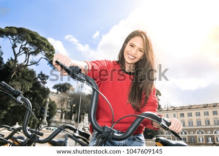 Riding bicycle in urban landscape, smiling young woman looking at camera