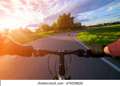 Riding A Bike First Person Perspective With Two Hands. Speed Motion Blur. Riding Bicycle Road Towards Sun.