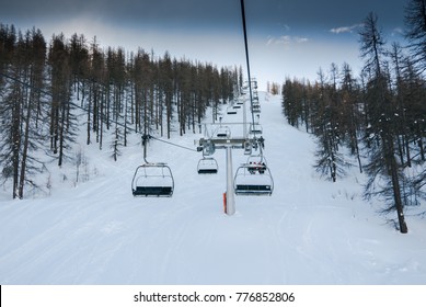 Riding The Chair Lift Through The Forest Of The High Alpine With Snow Covered Trees