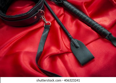 Riding Crop, A Whip Flogger, Leather Choker And Leash On Red Satin, Kinky Sex Toys For Dom / Sub Sexual And Other Forms Of Kink