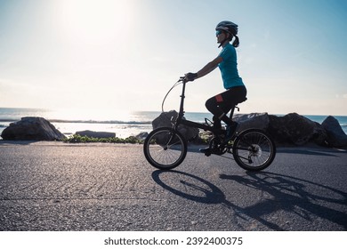 Riding folding bike on sunrise seaside road - Powered by Shutterstock