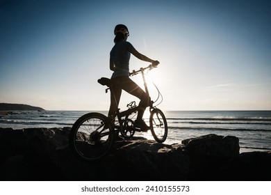 Riding folding bike on sunrise seaside road - Powered by Shutterstock