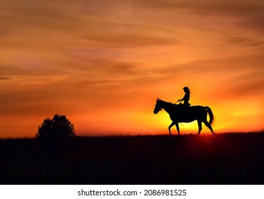 Riding horse at sunset, silhouette. A cowboy girl in a hat rides a horse against the background of a bright red beautiful sunset cloudy sky. - Powered by Shutterstock