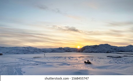 Riding A Snowmobile Under Sunset