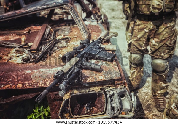 Rifle gun on destroy car by terrorist attack and
military officer at the scene

