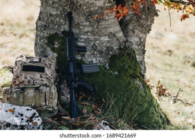 Rifle And Military Camo Backpack Under The Tree