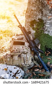 Rifle And Military Camo Backpack Under The Tree