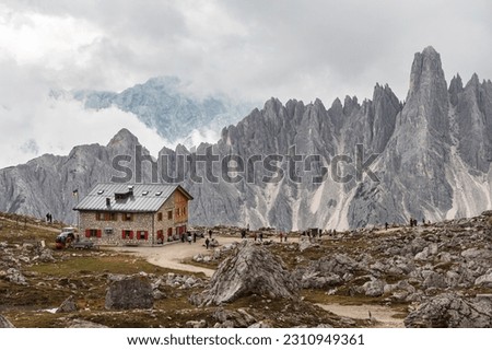 Rifugio Lavaredo with beautiful mountain peaks of Cadini group in Sexten Dolomites. Mountain hut with tourists on the loop trail around Tre Cime di Lavaredo, Dolomites, South Tyrol, Italy.