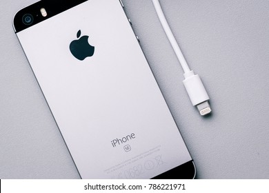 RIGA, JANUARY 2018 - A used Apple iPhone SE is displayed with battery indicator and Lightning charging cable illustrating phone charging for editorial purposes